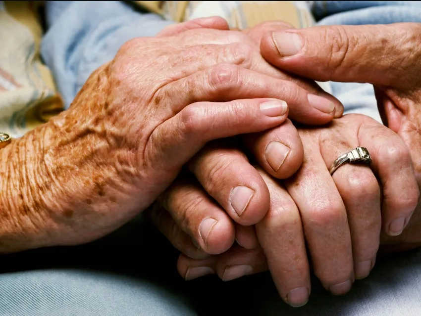 manos de anciano estrechadas con manos de persona joven