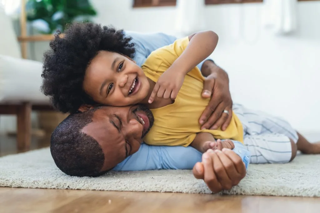 Padre e hijo en el piso jugando y sonriendo