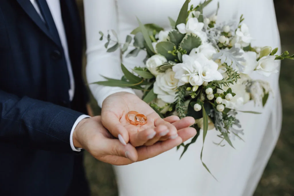 Manos de novios sosteniendo los anillos durante la ceremonia.